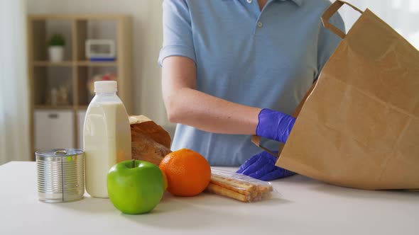 Woman in Gloves Taking Food From Paper Bag at Home