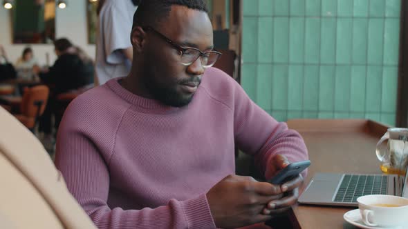 Black Businessman Using Smartphone in Cafe