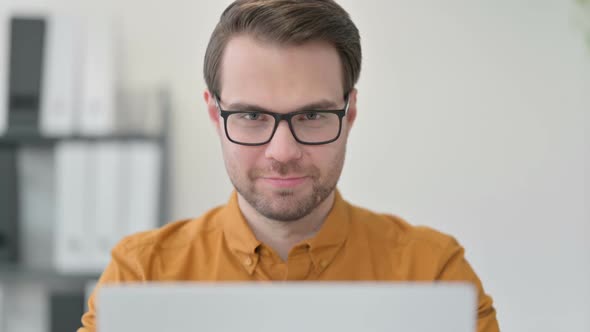 Close Up of Young Man with Laptop Smiling at the Camera