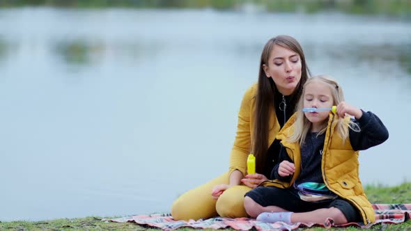 Mother and Daughter Inflate Soap Bubbles