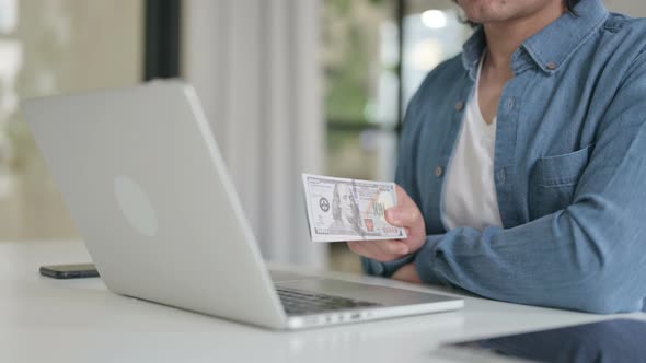 Close Up of Man Investing Dollars Through Laptop