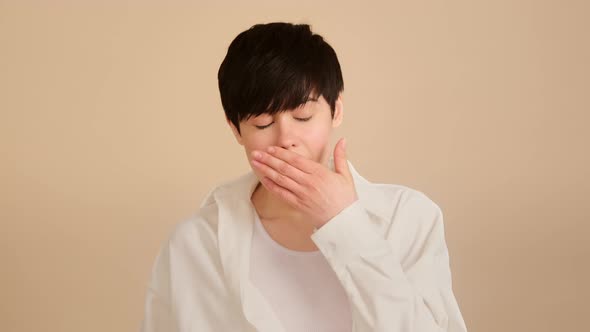 Young woman listens and yawns. Bored hipster yawning and covering mouth with palm
