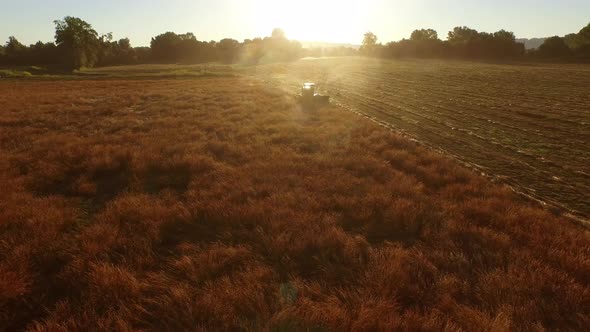 Aerial shot of combine in field at sunrise