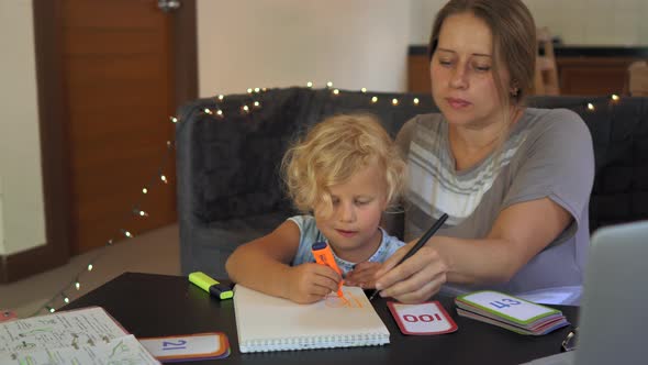 A Teacher, a Tutor for Home Schooling. a Teacher or Mom at the Table with a Little Girl