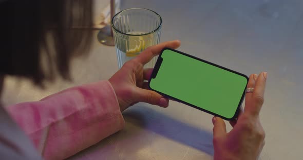 Woman Holding Smartphone with Chroma Key Screen at Cafe