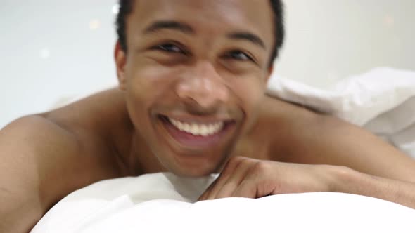 Victory Sign by Handsome African Man Lying in Bed