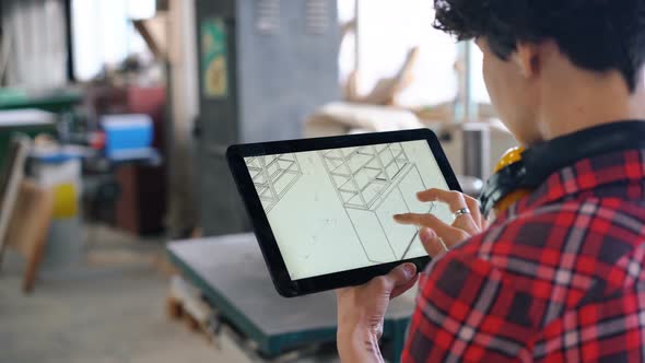 Woman Looking at Tablet Screen Checking Furniture Design in Wood Workshop