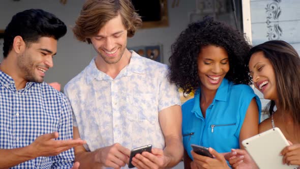 Friends interacting while using mobile phone and digital tablet at counter