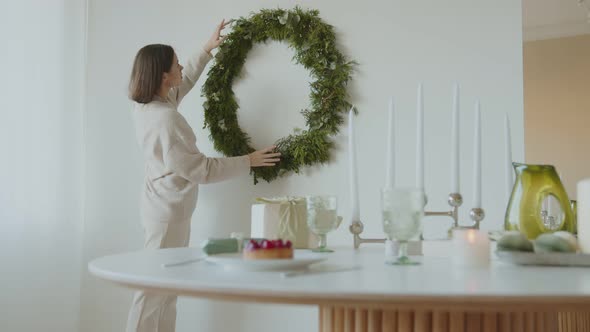 Young beautiful woman decorates a wreath for Christmas