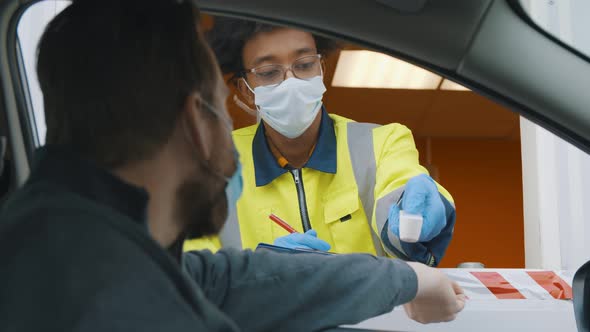 African Worker Wearing Safety Mask in Car Check Point Booth Scanning Temperature of Driver Man