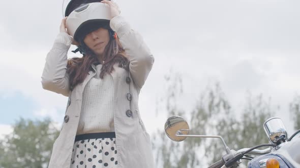 Confident Female Biker Taking Off Helmet in Slow Motion. Portrait of Beautiful Young Caucasian