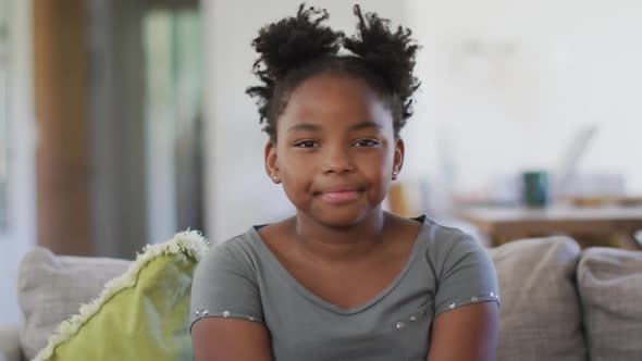 Portrait of happy african american girl sitting on sofa, smiling