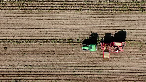 A potatoe harvesting tractor comes into the frame, top shot from above by drone with speed up and sl