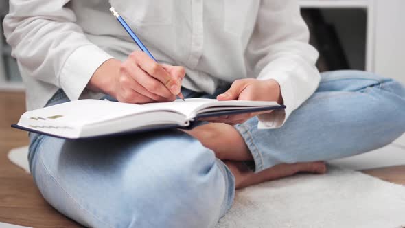 Businesswoman Sits On Floor In Lotus With Notebook, Writes Plans. European Woman Writes Pencil