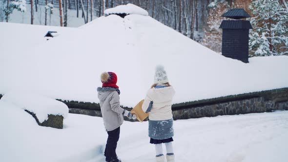 Little Boy and Girl are Running an Ahead Along the Path Near the Winter Forest