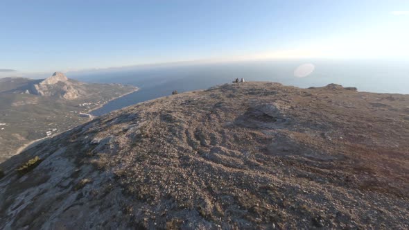 Cinematic Flight Around Movement Over Beautiful Natural Cliff Over Sea with Backpackers Couple