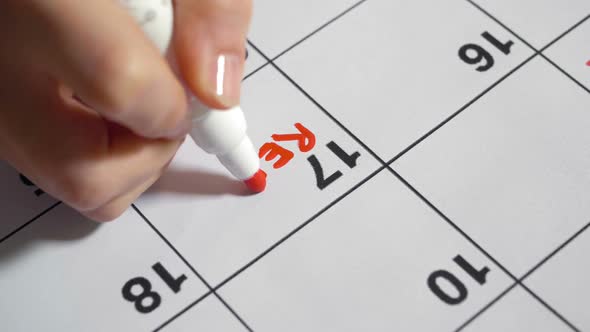 Woman Filling in Calendar with Red Marker