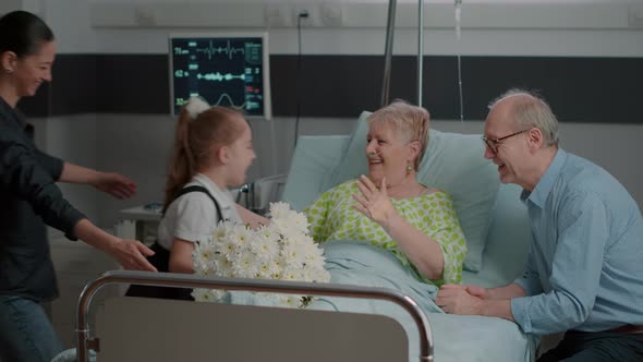 Close Up of Visitors Bringing Flowers to Sick Woman in Bed