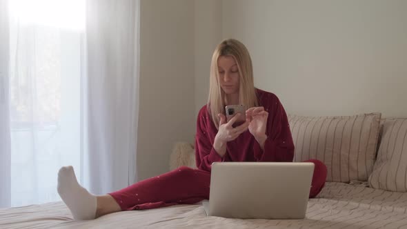 Woman in Bed with Phone and Laptop