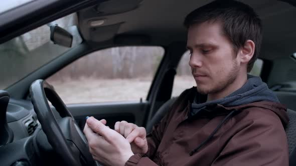 European man use smartphone, sitting in the car.