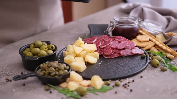 Making Meat and Cheese Antipasto Plater Woman Putting Pieces of Parmesan Hard Cheese on Stone