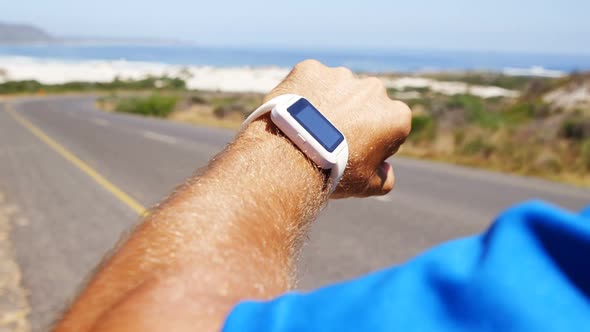 Triathlete man using smartwatch on a sunny day