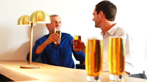 Two men interacting with each other while having beer at counter