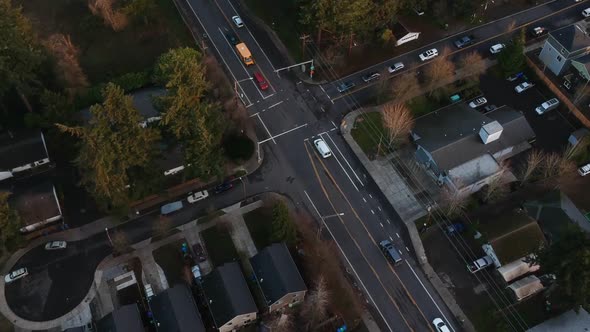 Aerial view of street intersection in city suburb during golden hour at sunset.