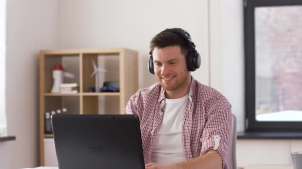 Happy Man in Headphones with Laptop at Office