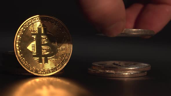 Gold Cryptocurrency Bitcoin Rotate on the Black Surface with Reflection. Man's Hand