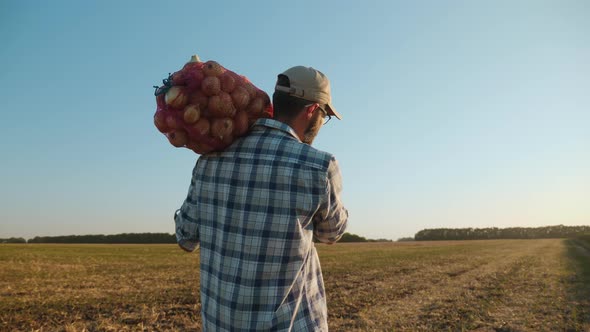 A Farmer Carries a Bag of Onions on His Shoulder