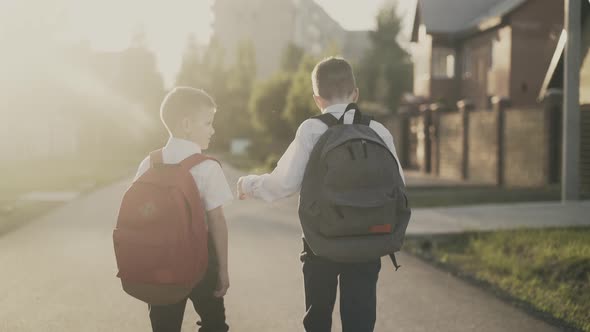 Back View: Two Schoolboys Return Home After Classes, They Talk.