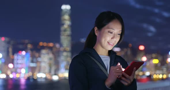 Woman look at cellphone in Hong Kong at night