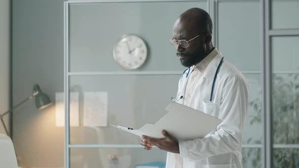 African American Doctor Working with Documents in Clinic