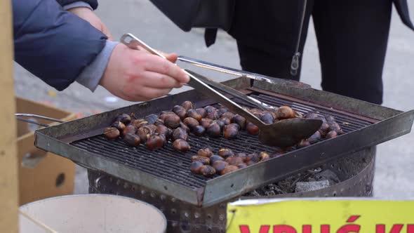 Local People Roast Chestnuts for Tourists on Grid on Street