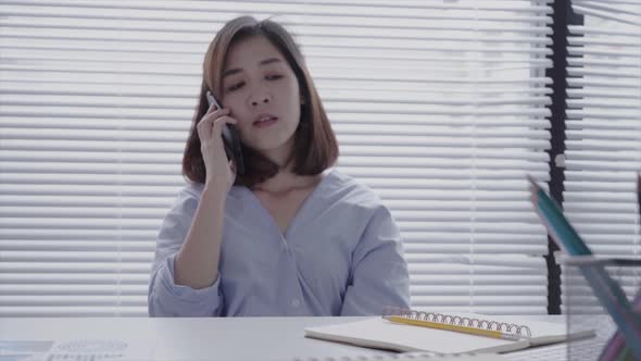 young asian woman working on laptop while sitting business woman using phone for work in home.