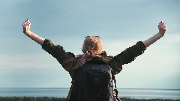 Active Woman Raising Hand Making Winner Gesture Over Natural Landscape