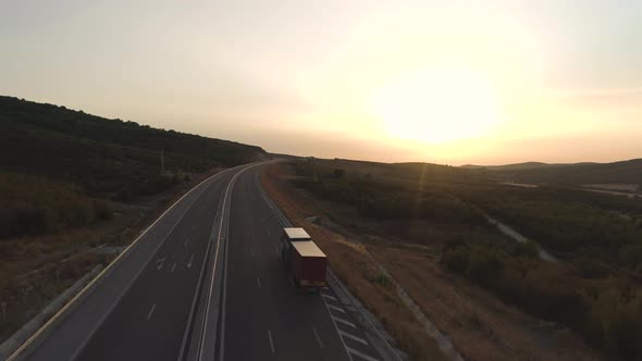 Aerial View of Cars Passing By Truck with Red Trailer Driving Slowly on Highway at Sunset