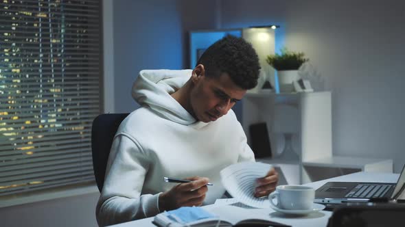 Medium Shot of Mixedrace Man with Medical Mask Signing Documents in Home Office