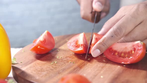 Hand Of Person Cutting Tomatoes On Chopping Board