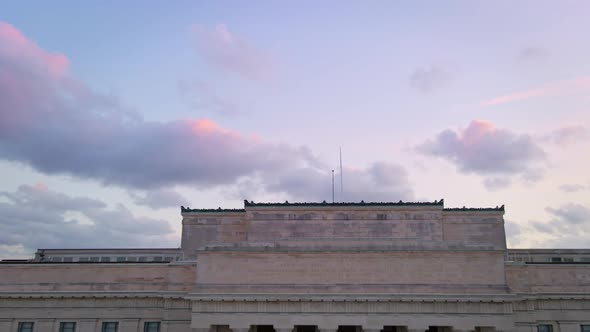 cinematic revealing aerial of Auckland cityscape behind war memorial museum under colorful horizon