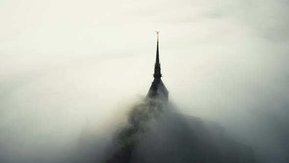 Aerial Shot of Sunrise Fog Clouds Covering Mysterious Heavenly Castle of Mont Saint Michel Fortress