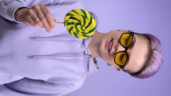 Vertical Shot of Young Woman Holding Lollipop Twirling Candy Indoors