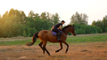 Woman riding horse by gallop through a meadow at sunset - PhotoDune Item for Sale