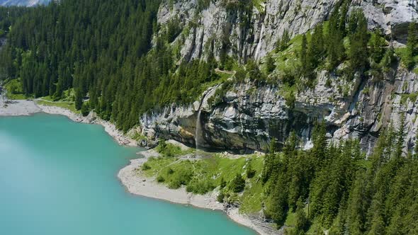 Flying up to group of people walking around waterfall in beautiful Swiss landscape