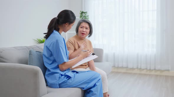 Asian caregiver nurse examine and listen senior woman patient at home.