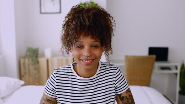 Cheerful Young Hispanic Latina Woman Smiling at Camera While Sitting on Bed