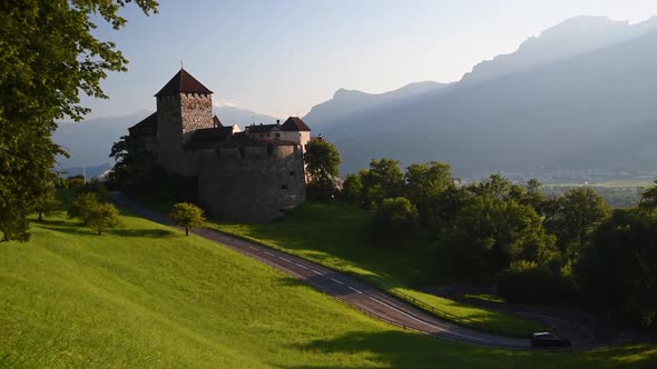 Wide angle view of the Castle of Vaduz. Light of the sunset over the mountains and lush green meadow