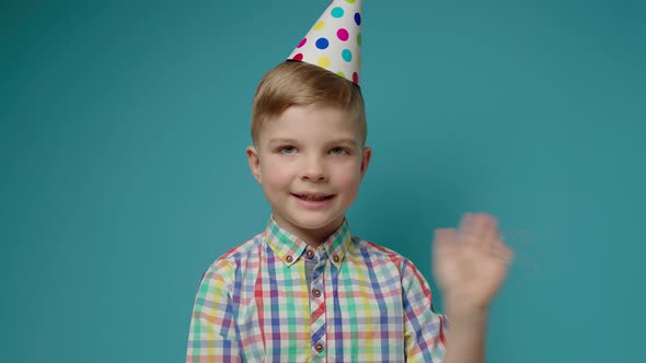 Preschool Boy Greeting Someone with Happy Birthday Talking to Camera and Blowing Birthday Pipe on