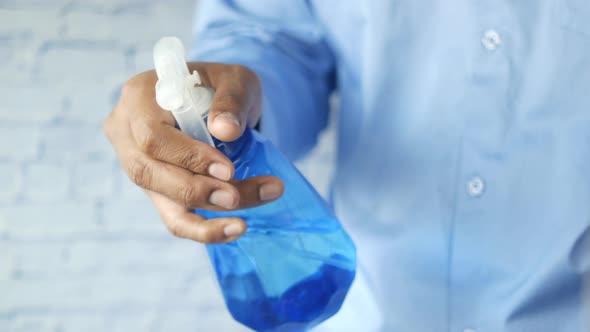 Hand in Blue Rubber Gloves Holding Spray Bottle with Copy Space